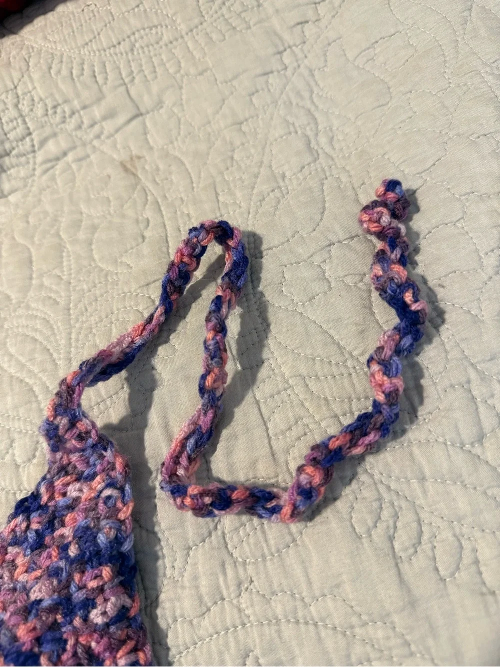 Handmade crochet bandana in pink, blue, and purple marbled yarn.